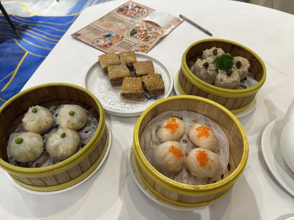 Assortment of dim sum dishes in bamboo steamers on a white table